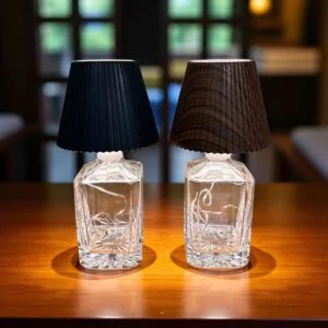 Lampade LED RGB inserite in bottiglie di vetro accese su tavolo in ambiente bar